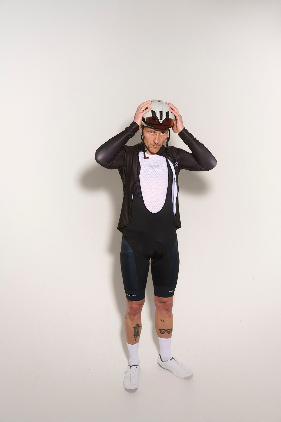 Person wearing a black cycling suit and helmet, and white baselayer